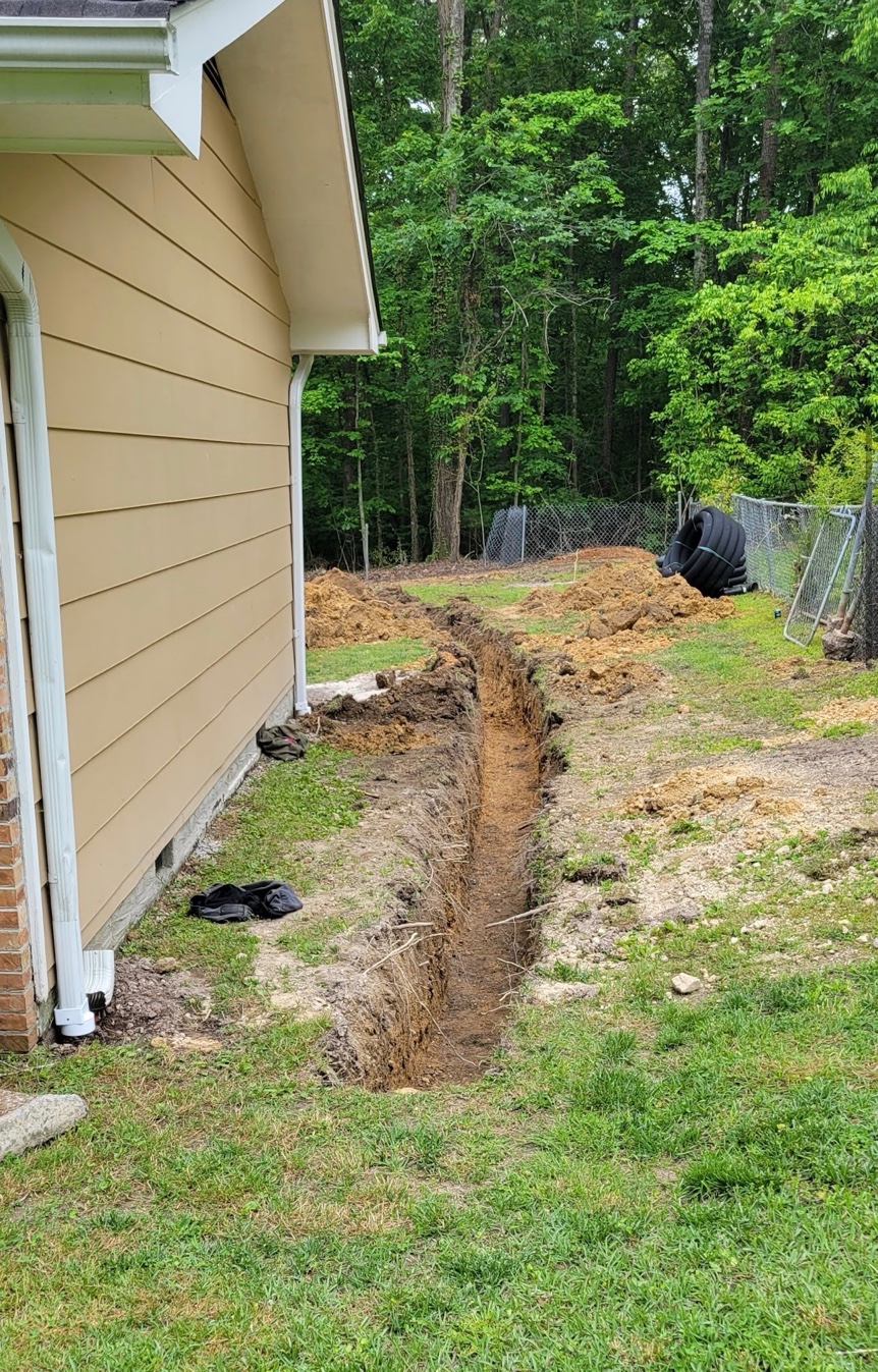 Drainage trench excavated along the side of a home in Ooltewah TN ready for French drain pipe installation