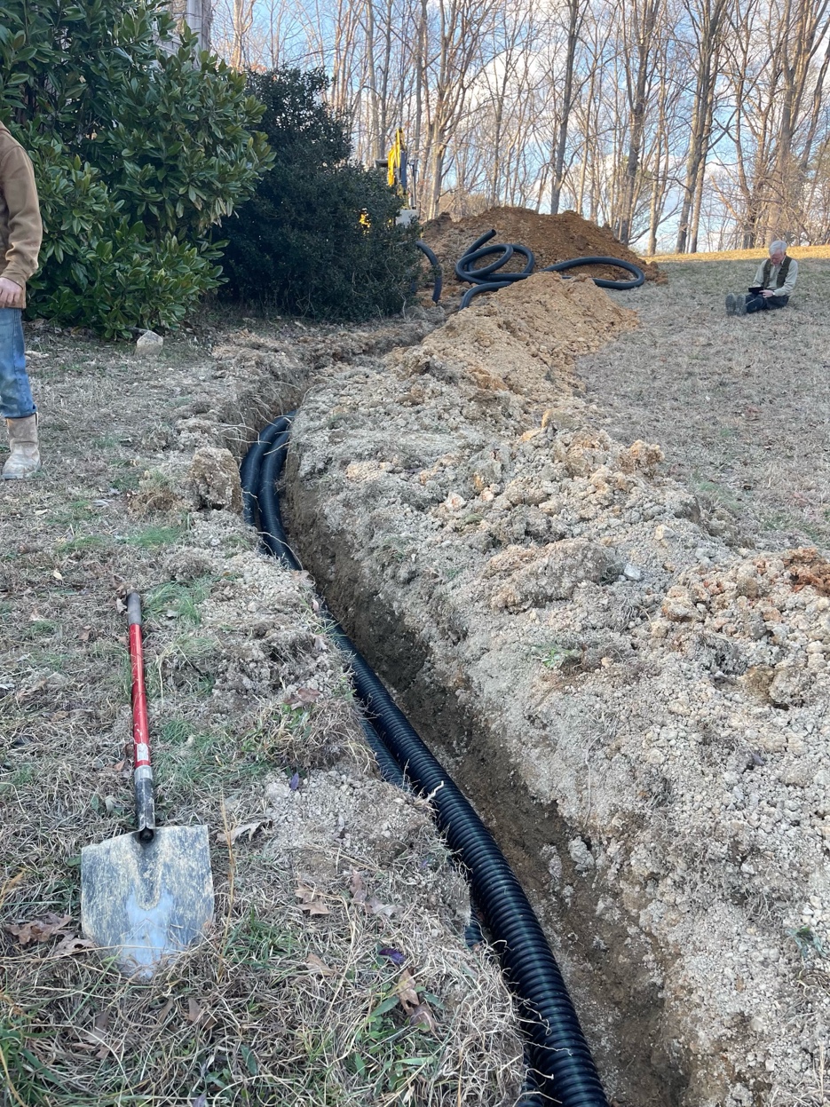 Corrugated solid pipe laid in a trench through the yard with excavated soil staged alongside in Ooltewah TN